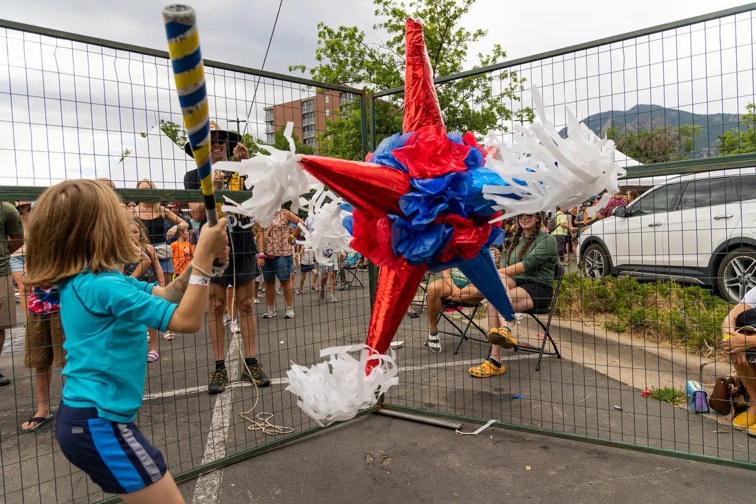 A kid mid-swing at the festival piñata